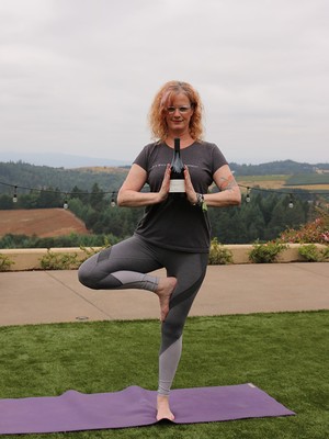 Suzanne doing yoga while holding a bottle of wine