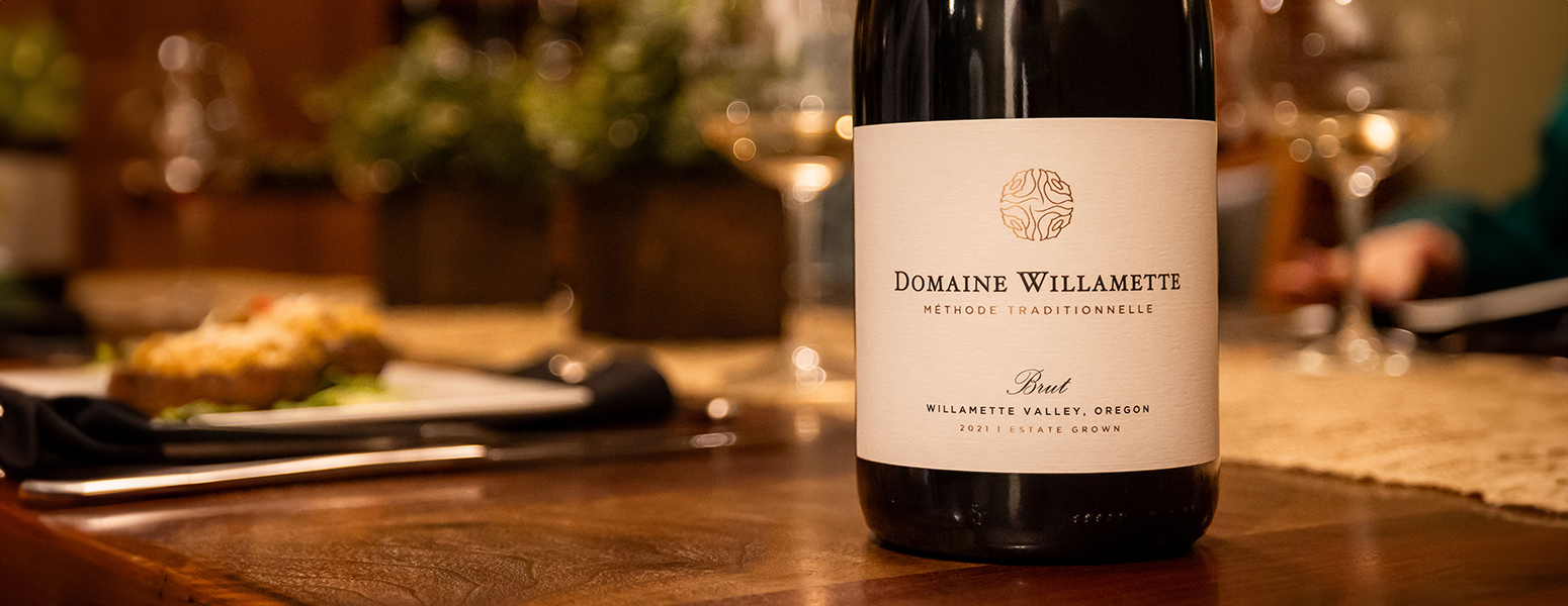 A hand pulling a bottle of Willamette Valley Vineyards Wines from a wine rack.