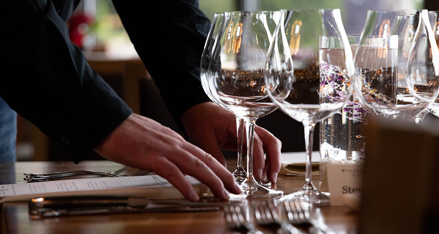 A hand setting a table in preparation for a Willamette Valley Vineyards Pairings Dinner