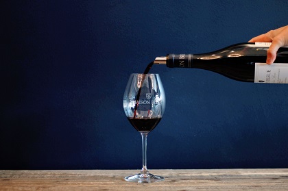 Red wine poured into a glass with blue background