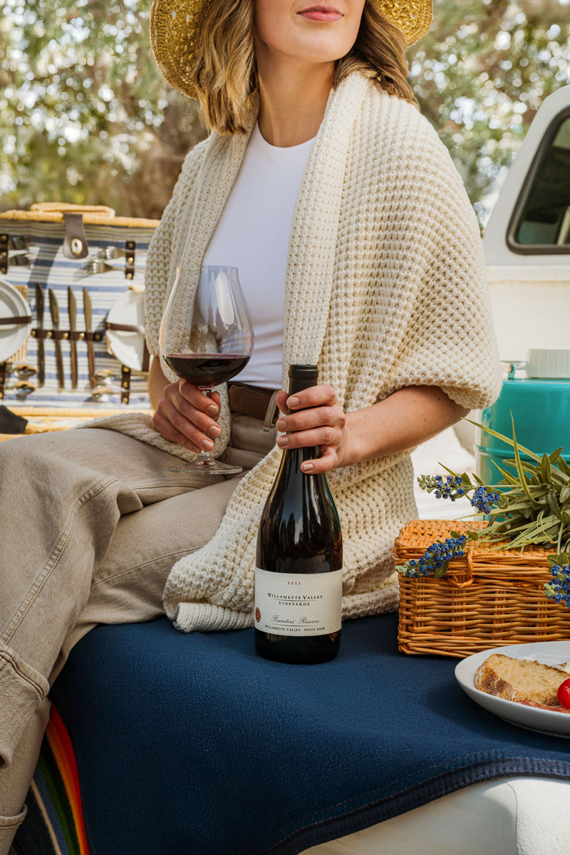 A woman sitting down holding a glass of Willamette Valley Vineyards wine.