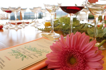 Image of a vibrant pink flower on a table filled with wine glasses prepared for the July Pairings Dinner at Willamette Valley Vineyards