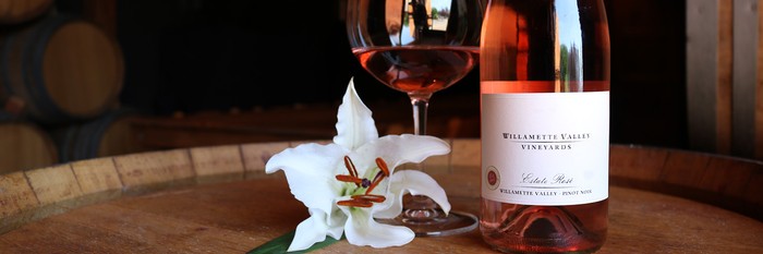 Bottle of Estate Rosé with a white Lilly and glass of wine