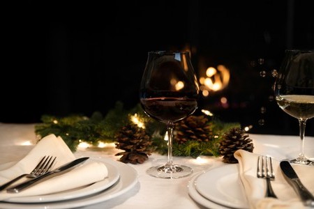 A table set up with winter decorations, wine glasses and table settings prepared for a Winter Wine Pairings Dinner. 