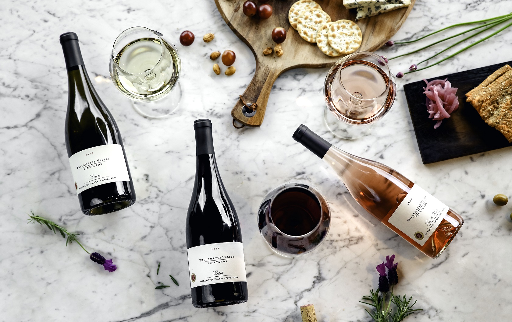 Wine bottles, glasses, and food laid on a table
