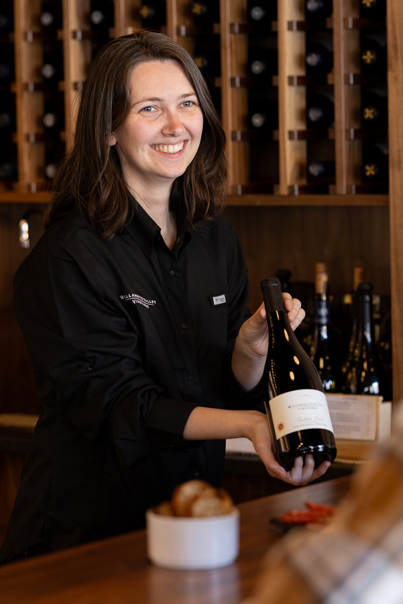 Person holding a wine bottle out to a customer